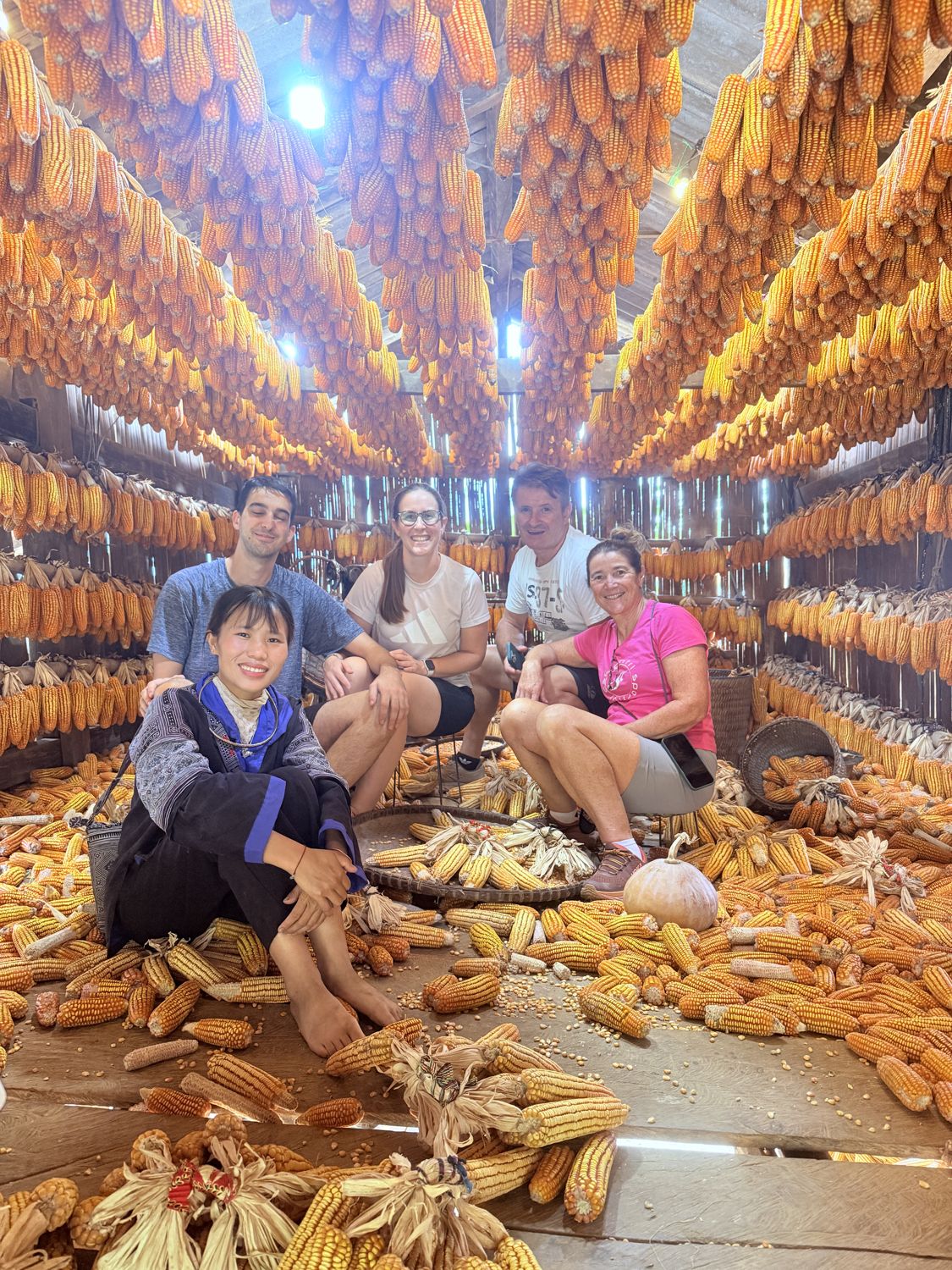 Guests sitting under rows of hanging corn at Nhà Ngô Màng Mủ